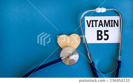 Vitamin B5 pantothenic acid symbol. Concept words Vitamin B5 on beautiful white card. Wooden heart and stethoscope. Beautiful blue background. Medical healthy lifestyle Vitamin B5 concept. 136958135