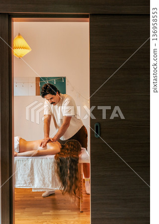 Male Therapist Giving Relaxing Back Massage to Woman 136958553