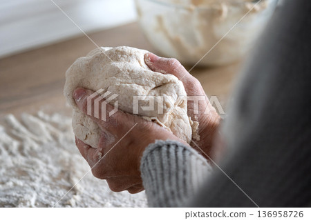 Woman kneading dough in kitchen preparing homemade bread Woman kneading dough in kitchen preparing homemade bread 136958726