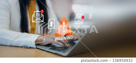 Email phishing warning icon overlay. Cybersecurity alert, Businesswoman using laptop with internet scam and fraud notification concept in modern office workspace. 136958932
