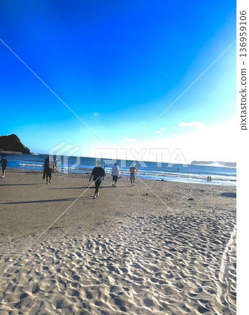 A family walking on the beach under a blue sky 136959106