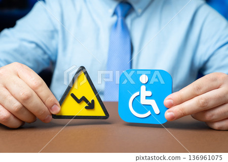 Warning sign of declining status and symbol of a person with a disability. Reduction in payments and social benefits. Economic hardship and social support cuts 136961075