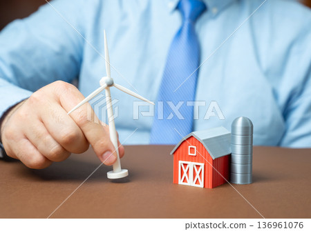 A farm and a windmill. Construction of renewable energy sources for farms. Sustainable agriculture and green power generation. Energy independence for rural business 136961076