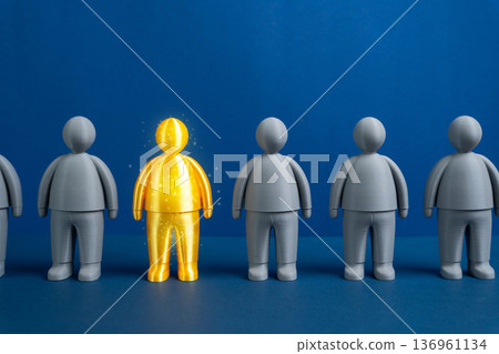 A golden figurine of a man standing out from the crowd. A valuable worker and talented collaborator. Top performer recognition and human capital excellence 136961134