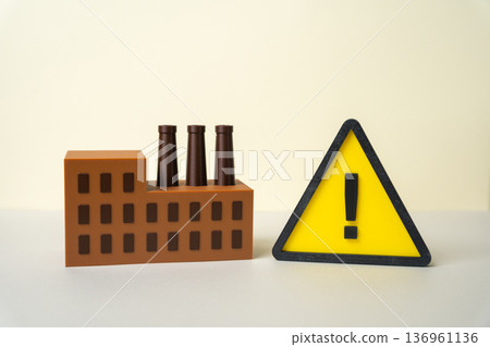 Industrial plant building and yellow attention sign. Problems in the industrial sector. Threat of man made disaster and overleveraging. High corporate debt risk and economic instability warning Industrial plant building and yellow attention sign. Problems in the industrial sector. Threat of man made disaster and overleveraging. High corporate debt risk and economic instability warning 136961136