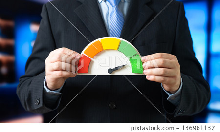 A businessman with a scale showing the highest green level. Success and maximum efficiency. Performance growth and productivity achievement. Business excellence and KPI optimization A businessman with a scale showing the highest green level. Success and maximum efficiency. Performance growth and productivity achievement. Business excellence and KPI optimization 136961137