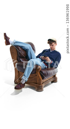 Teenage boy relaxing in armchair using smartphone isolated on white. Teenage boy relaxing in armchair using smartphone isolated on white. 136961998