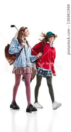 Teen girls in preppy style walking with golf equipment isolated on white. Teen girls in preppy style walking with golf equipment isolated on white. 136961999