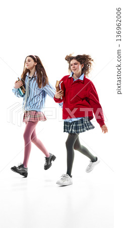 Teen girls in preppy school outfits walking with books isolated on white. 136962006