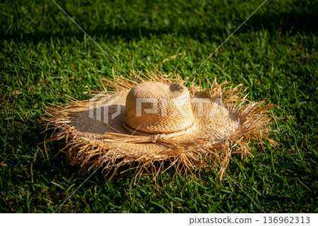 Straw sun hat resting on green grass in mexico sunshine Straw sun hat resting on green grass in mexico sunshine 136962313