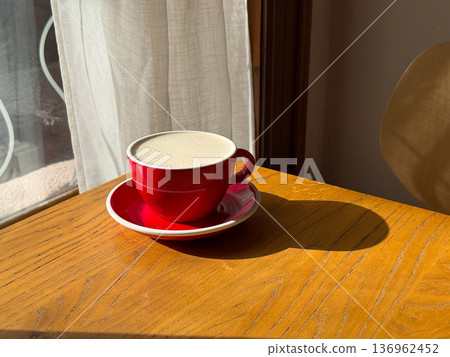 Close up red coffee cup casting shadow on table. Morning caffeine ritual, cafe lifestyle, warmth, minimal composition, comfort break 136962452