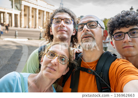 Berlin, germany, august 15, 2023. Family selfie at brandenburg gate in berlin, parents and teens smiling together on a sunny vacation, iconic landmark sightseeing moment 136962663