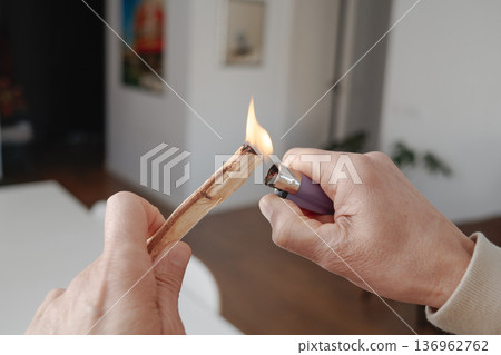 a man lights a sandalwood stick indoors 136962762