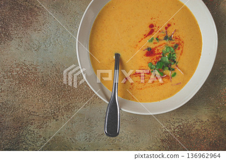 pumpkin cream soup, in a white bowl on a textured background, top view, homemade, no people, rustic style, 136962964