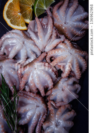 Fresh baby octopus, on black slate, with lemon and greenery, top view, no people, Fresh baby octopus, on black slate, with lemon and greenery, top view, no people, 136962968