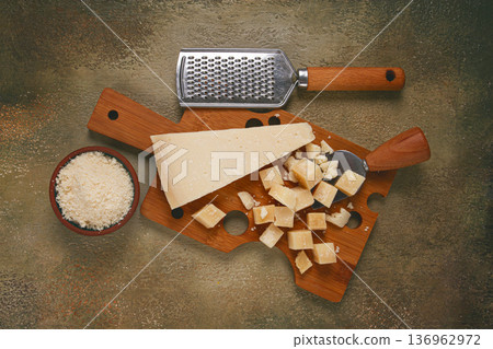 Freshly sliced and grated cheese, parmesan cheese, on a wooden chopping board, rustic style, no people 136962972