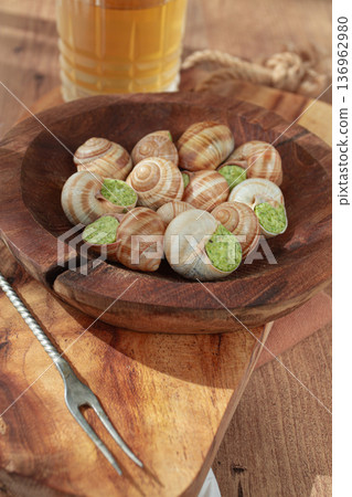Snails cooked with herb oil on a wooden plate, served with white wine, natural light, no people, Snails cooked with herb oil on a wooden plate, served with white wine, natural light, no people, 136962980