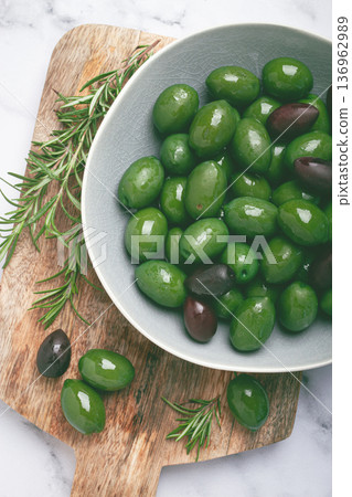 Chalkidiki olives, classic Greek green olives, in a bowl on a cutting board, top view, without people, Chalkidiki olives, classic Greek green olives, in a bowl on a cutting board, top view, without people, 136962989