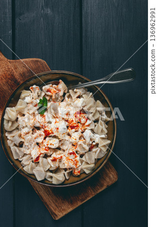 Traditional Turkish dumplings served with yogurt and spicy sauce on a green decorative plate Traditional Turkish dumplings served with yogurt and spicy sauce on a green decorative plate 136962991