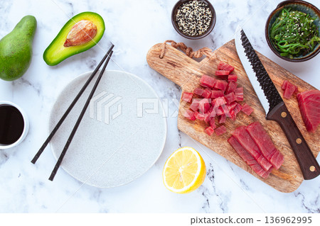 Cooking fresh tuna with ingredients on a marble countertop, ingredients for making sushi and tuna tartare Cooking fresh tuna with ingredients on a marble countertop, ingredients for making sushi and tuna tartare 136962995