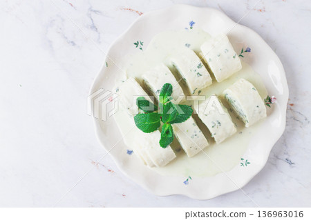 Gebjalia, a traditional Megrelian dish, cold appetizer of cheese with mint, Georgian cuisine, on a white plate, homemade. Gebjalia, a traditional Megrelian dish, cold appetizer of cheese with mint, Georgian cuisine, on a white plate, homemade. 136963016