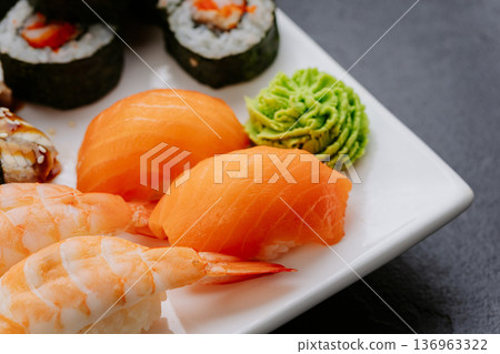 Closeup sushi set with salmon shrimp nigiri and rolls served on white plate Closeup sushi set with salmon shrimp nigiri and rolls served on white plate 136963322