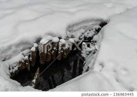 A snow-covered well with wooden logs A snow-covered well with wooden logs 136963445
