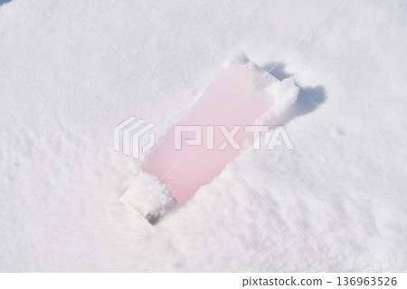 Pink cosmetic tube laying in fresh snow 136963526