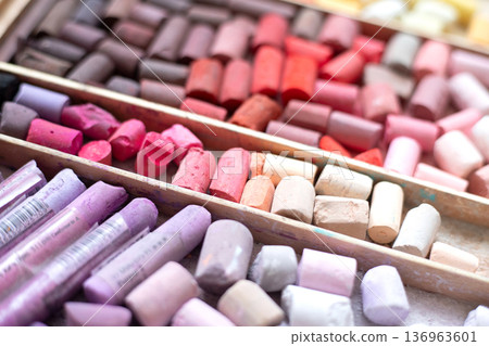 Soft pastel chalk set in pink, red, yellow, and brown in a wooden art supply case. Multicolored artist's background Soft pastel chalk set in pink, red, yellow, and brown in a wooden art supply case. Multicolored artist's background 136963601