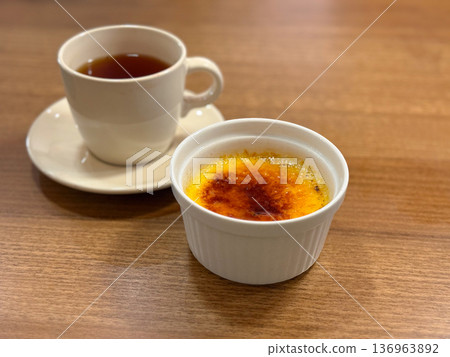 Creme brulee with caramel crust and cup of tea. French dessert, sweet indulgence and cafe lifestyle concept. Creme brulee with caramel crust and cup of tea. French dessert, sweet indulgence and cafe lifestyle concept. 136963892