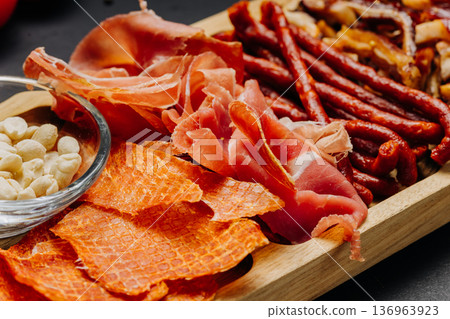Assorted cured meats and snacks served on wooden board gourmet appetizer platter Assorted cured meats and snacks served on wooden board gourmet appetizer platter 136963923