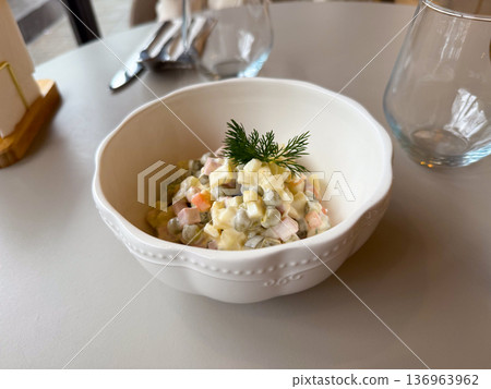 Traditional russian salad in white bowl with dill garnish. Comfort food, festive cuisine and homemade dining tradition. 136963962