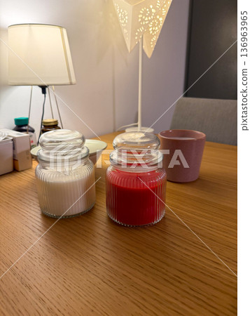 Glass jar candles on wooden table at night. Cozy interior lighting, relaxation ritual, home comfort concept 136963965