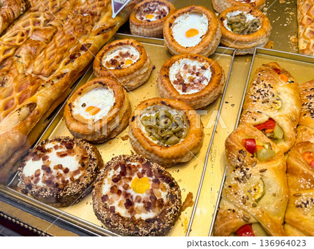 Close up of savory pastry with egg and bacon in bakery case. Breakfast option, street snack, comfort food, culinary craftsmanship, gastronomy tradition 136964023