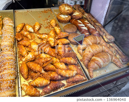 Bakery display with croissants, cheese rolls and pretzel sticks. Fresh assortment, street food culture and european artisan baking concept. Bakery display with croissants, cheese rolls and pretzel sticks. Fresh assortment, street food culture and european artisan baking concept. 136964048
