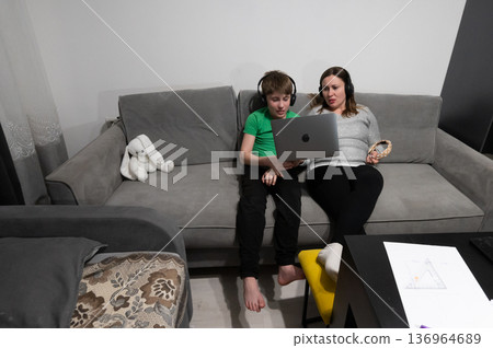 Engaging online learning experience shared between a child and a parent in a cozy living room during evening hours Engaging online learning experience shared between a child and a parent in a cozy living room during evening hours 136964689