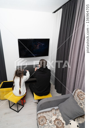 Siblings enjoy a fun gaming night together in a cozy living room, creating memories filled with laughter and friendly competition during the winter months 136964705