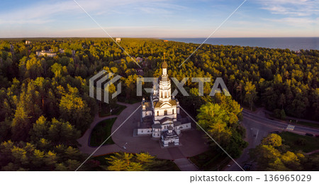 Aerial panoramic top view to Church of the Kazan Icon of Mother of God. Theotokos Cathedral main attraction of city. Rising above green forest. Zelenogorsk, Terijoki, Russia, St. Petersburg. Europe. Aerial panoramic top view to Church of the Kazan Icon of Mother of God. Theotokos Cathedral main attraction of city. Rising above green forest. Zelenogorsk, Terijoki, Russia, St. Petersburg. Europe. 136965029