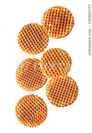 Multiple round caramel stroopwafels arranged in a scattered pattern from above, on a white background. Concept of sweet snacks 136965555