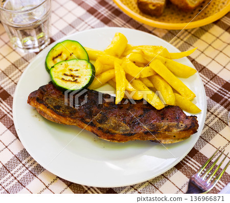 Traditional Spanish dish is Churasco with French fries and zucchini 136966871