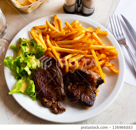Baked beef steaks with french fries, lettuce and hollandaise sauce 136966883