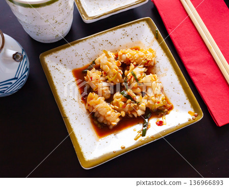 Squid in spicy sauce served on a white plate with onions Squid in spicy sauce served on a white plate with onions 136966893