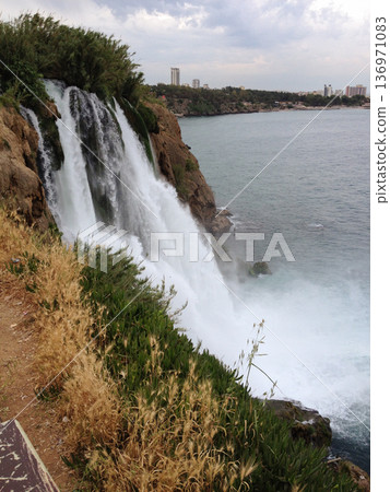 Duden Waterfall crashes down rocky cliff near city in Turkey in the province of Antalya . Force, motion, gravity, solitude, erosion, time, connection, awe, freedom, and escape from urban routine Duden Waterfall crashes down rocky cliff near city in Turkey in the province of Antalya . Force, motion, gravity, solitude, erosion, time, connection, awe, freedom, and escape from urban routine 136971083