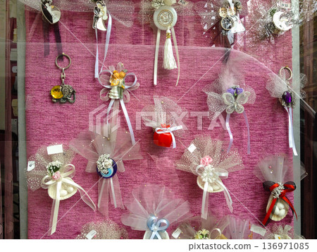 Decorative wedding souvenirs in a shop window. Expression of celebration, love, and cultural aesthetics through symbolic details. 136971085