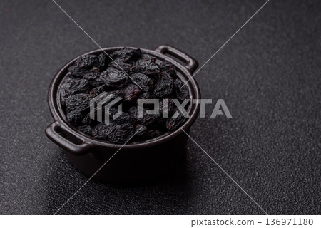 Sweet, dry black or blue raisins made from grapes are a healthy and nutritious food. Black raisins Sweet, dry black or blue raisins made from grapes are a healthy and nutritious food. Black raisins 136971180