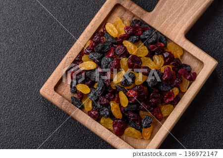 Dried cranberries, yellow and black sweet raisins as ingredients for a breakfast. Raisins and cranberries Dried cranberries, yellow and black sweet raisins as ingredients for a breakfast. Raisins and cranberries 136972147