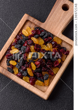 Dried cranberries, yellow and black sweet raisins as ingredients for a breakfast. Raisins and cranberries Dried cranberries, yellow and black sweet raisins as ingredients for a breakfast. Raisins and cranberries 136972148