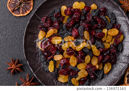 Dried cranberries, yellow and black sweet raisins as ingredients for a breakfast. Raisins and cranberries Dried cranberries, yellow and black sweet raisins as ingredients for a breakfast. Raisins and cranberries 136972163