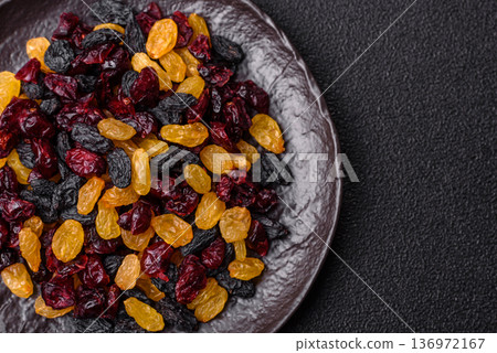 Dried cranberries, yellow and black sweet raisins as ingredients for a breakfast. Raisins and cranberries Dried cranberries, yellow and black sweet raisins as ingredients for a breakfast. Raisins and cranberries 136972167