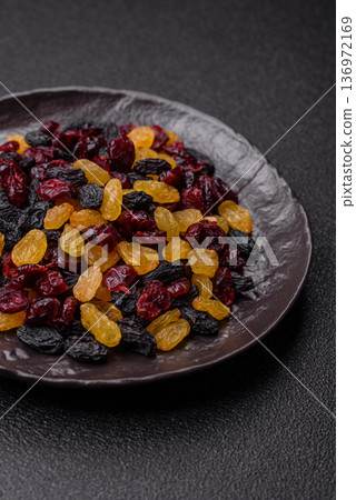 Dried cranberries, yellow and black sweet raisins as ingredients for a breakfast. Raisins and cranberries 136972169